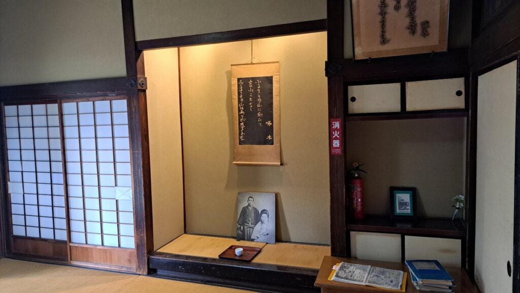 A hanging scroll featuring a famous *tanka* poem and a photo panel of the couple.