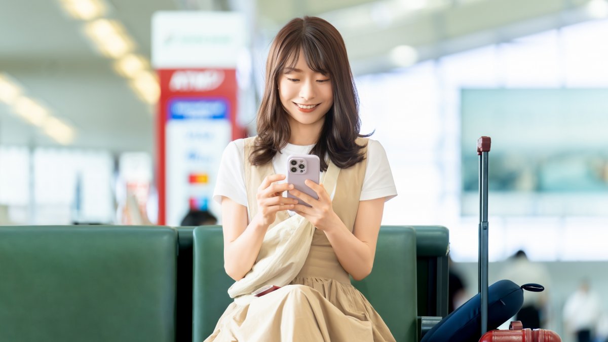 空港でスマホを触る女性のイメージ